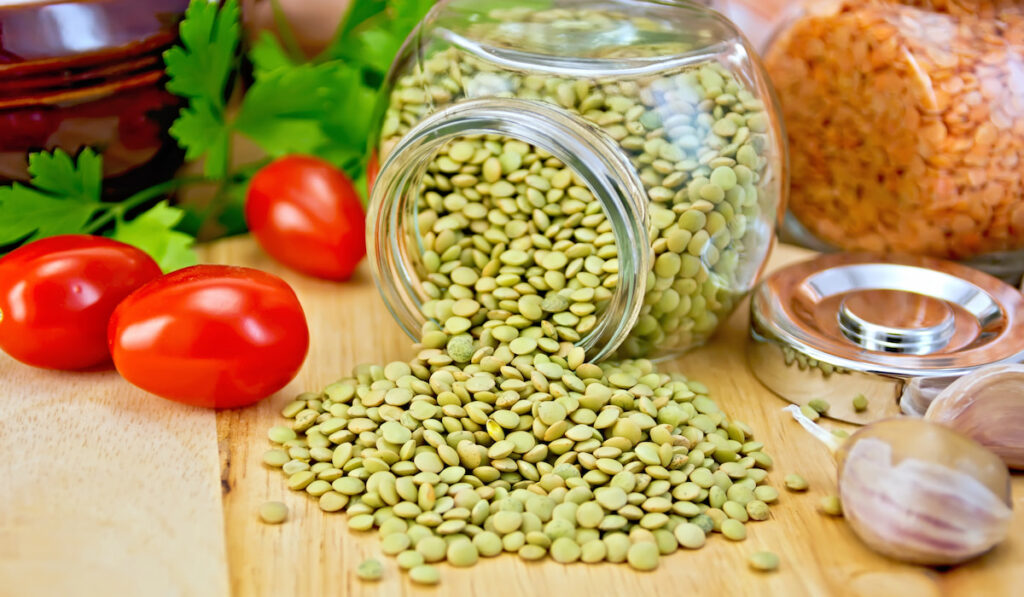 Lentils green in jar with garlic and tomato on board 