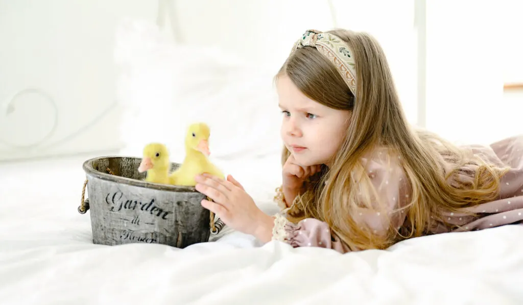 Little girl on the bed with little ducks