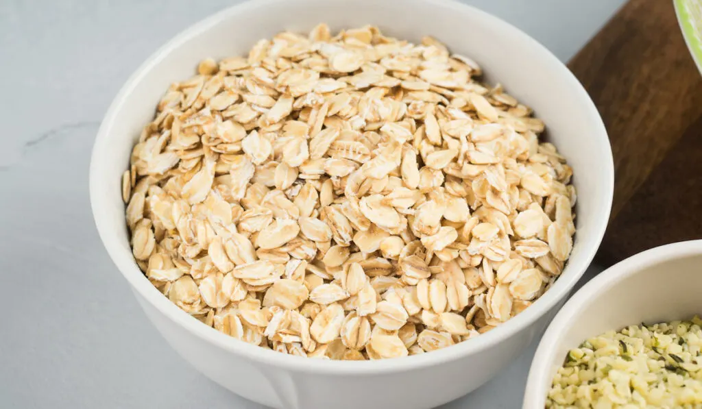 Oat flakes in bowl on gray background