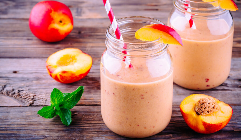 Peach smoothies in a mason jar with mint on wooden background 