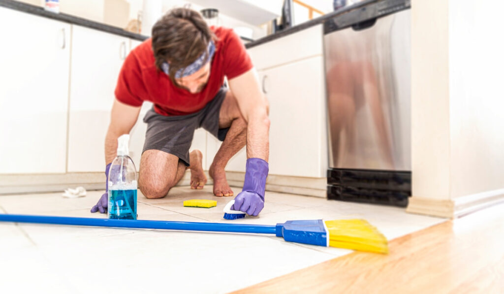 Person on hands and knees scrubbing floor tile