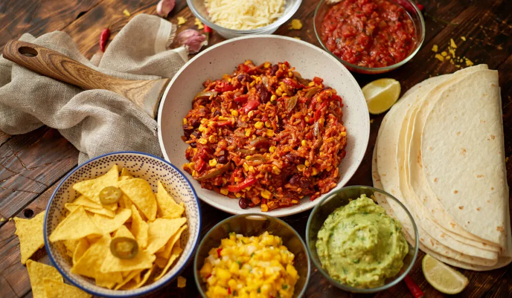 Preparing vegetable burritos on white pan. With various ingredinets for mexican food 