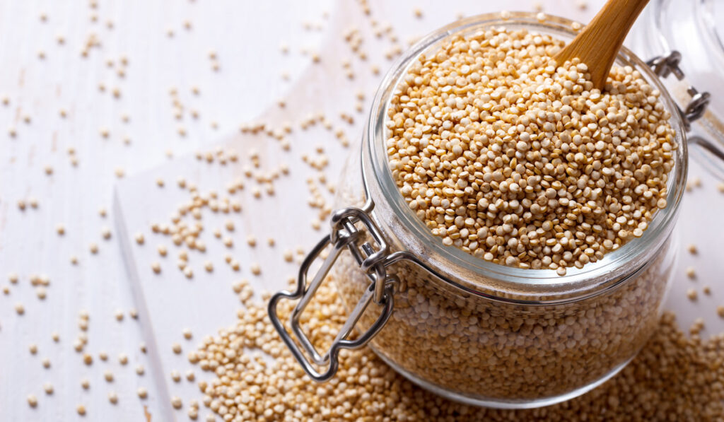 Quinoa seeds in glass container on white background 