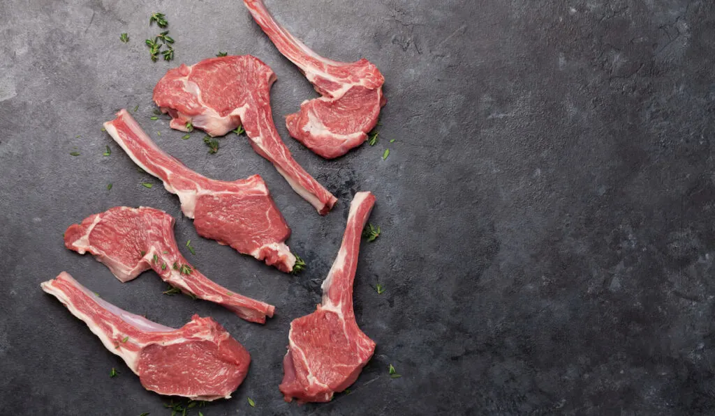 Raw rack of lamb ribs on black background