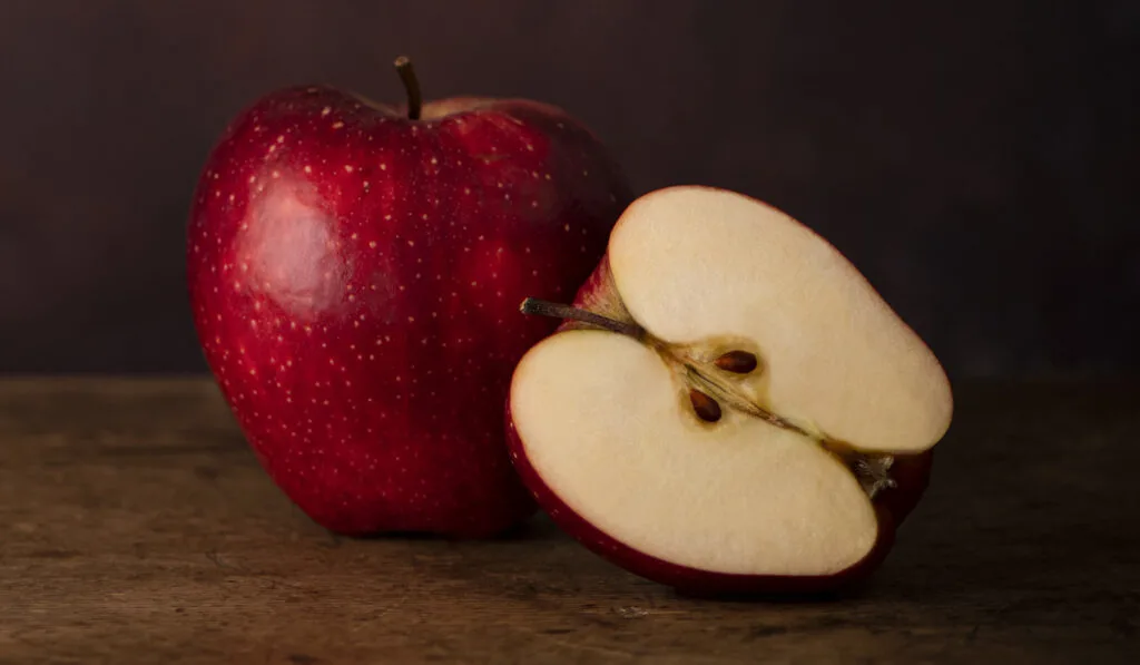 Red Whole Apple and Half Apple on a Wooden Old Surface 