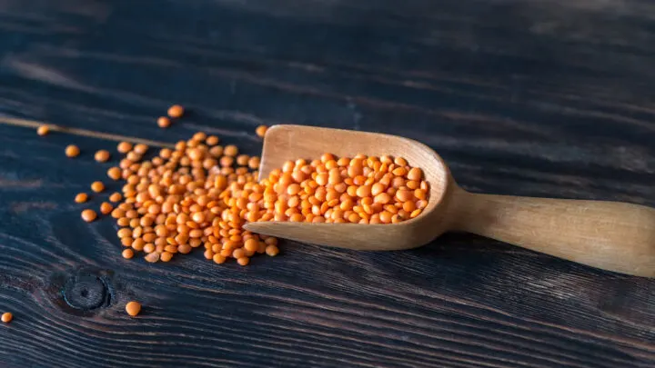 Red-lentils-in-a-wooden-scoop-on-black-table
