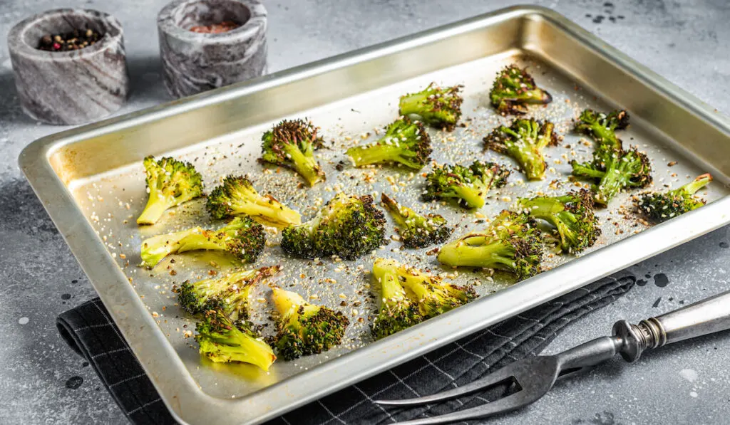 Roasted broccoli with garlic in baking tray on gray background