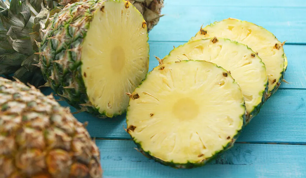 Slices of fresh pineapple on blue table