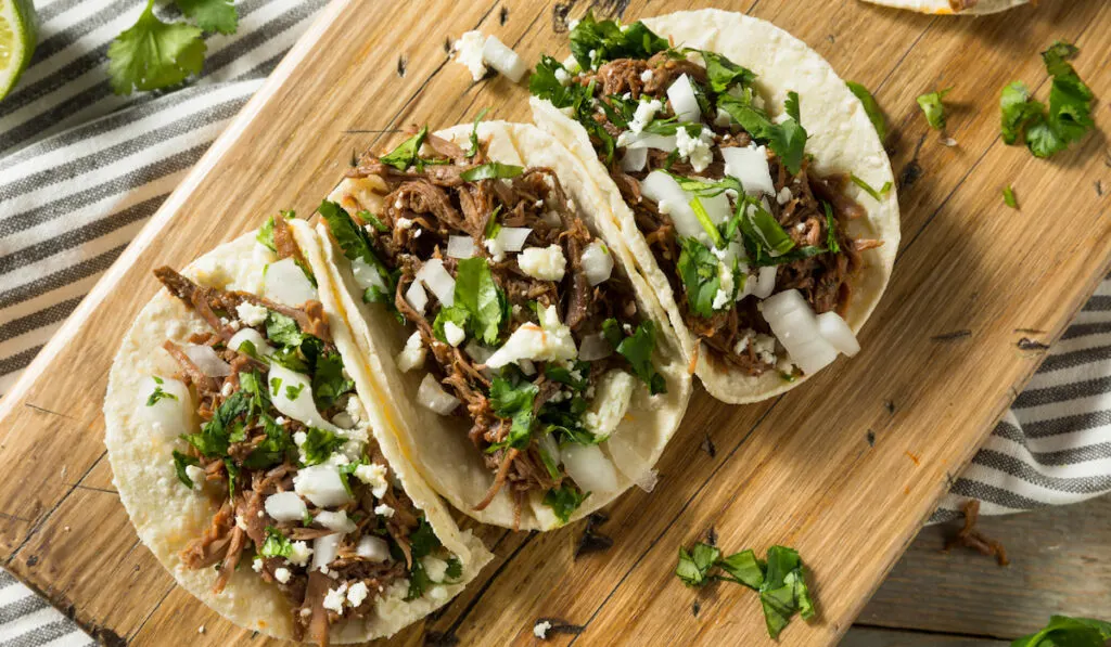 Spicy Homemade Beef Barbacoa Tacos on wooden choppingboard 