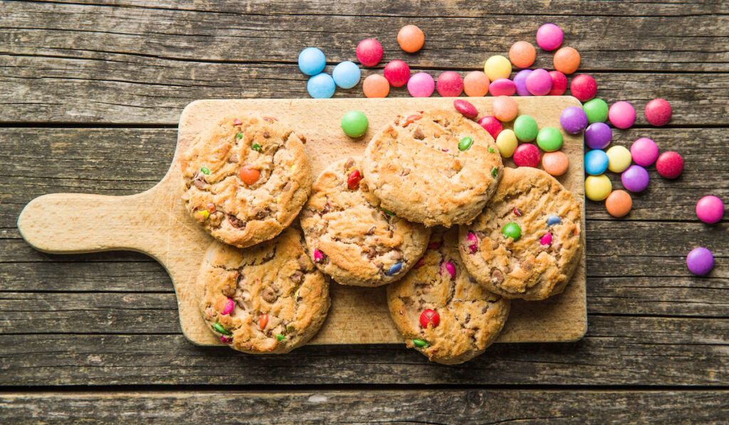 Sweet cookies with colorful candies on wooden background