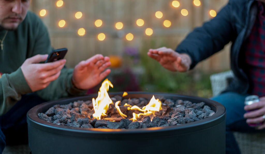 Two guys hanging out around a backyard fire pit 
