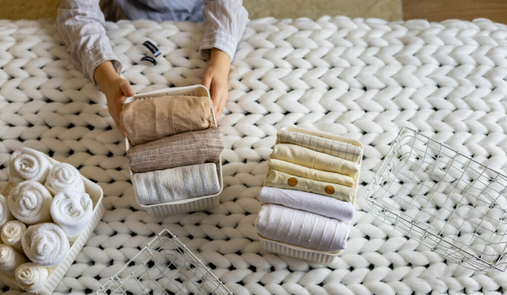 Woman hands neatly folded linens and towels 