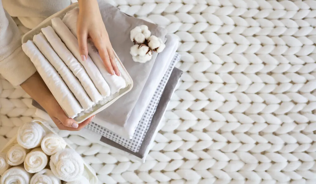 Woman hands neatly folded linens and towels 