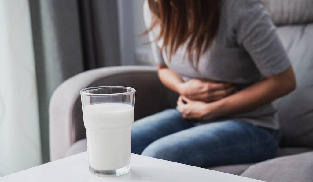 Woman having bad stomach ache after drinking glass of milk