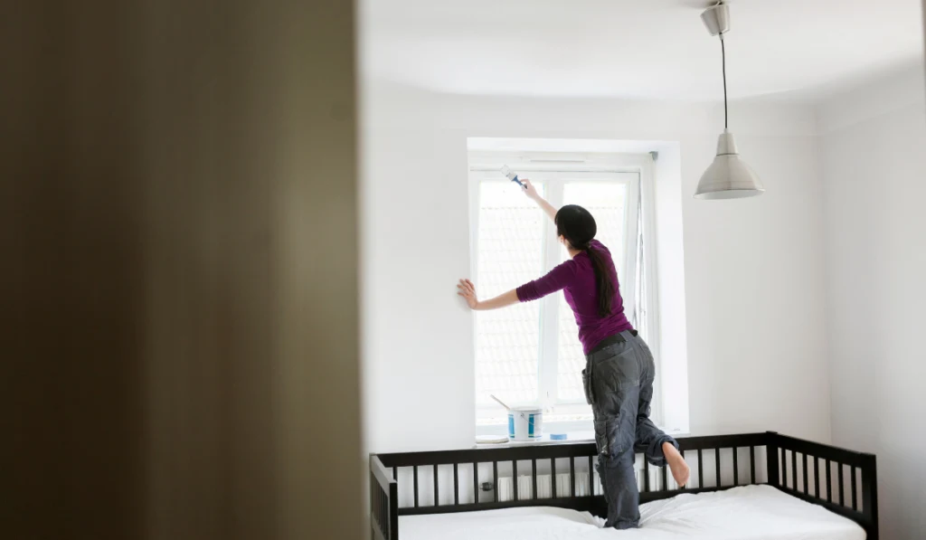 Woman painting window white
