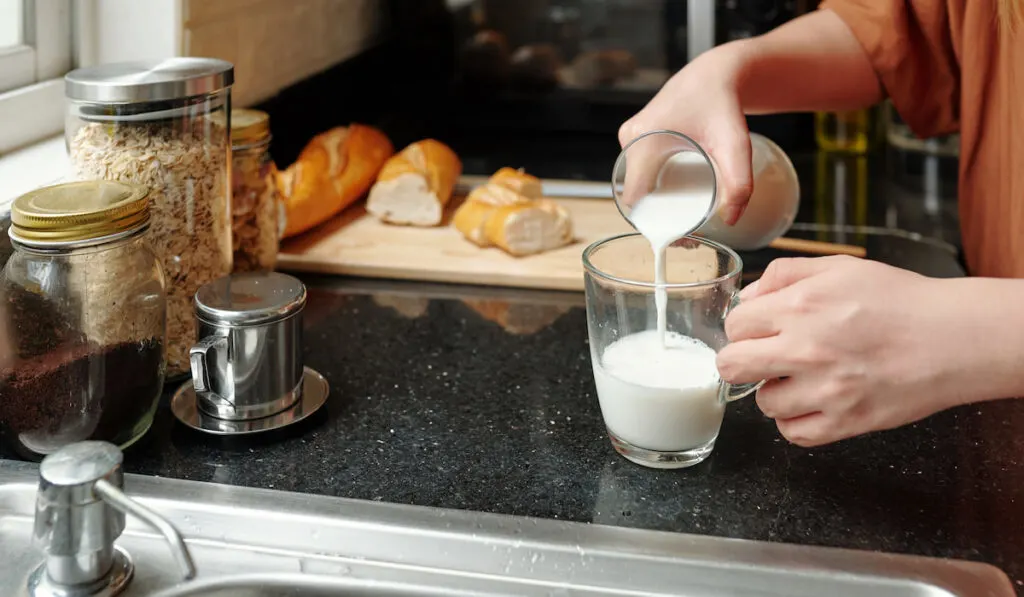 Woman pouring milk in glass in the kitchen 