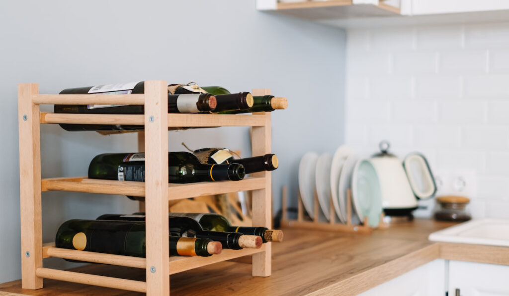 Wooden wine shelves with bottles on the table in modern kitchen