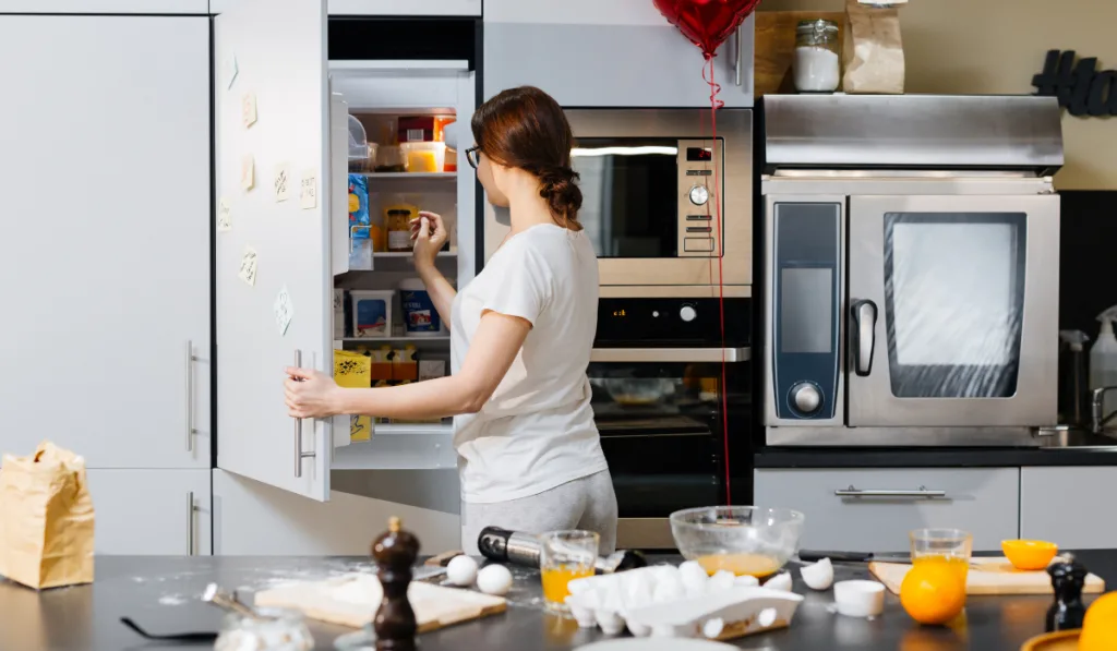 Young woman opening fridge to take something

