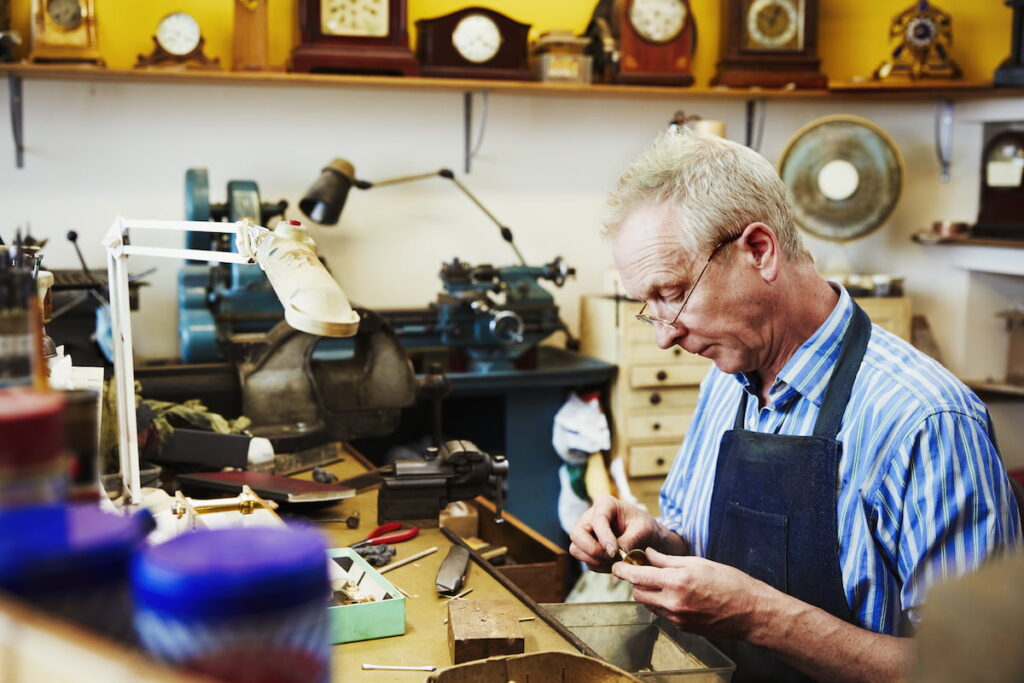 a clock maker working repairing the small parts of clock