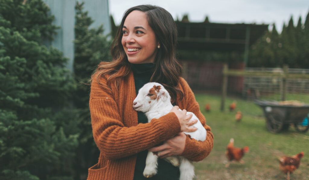 beautiful woman holding a baby goat 