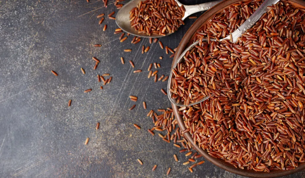 brown rice in wooden bowl and two spoons