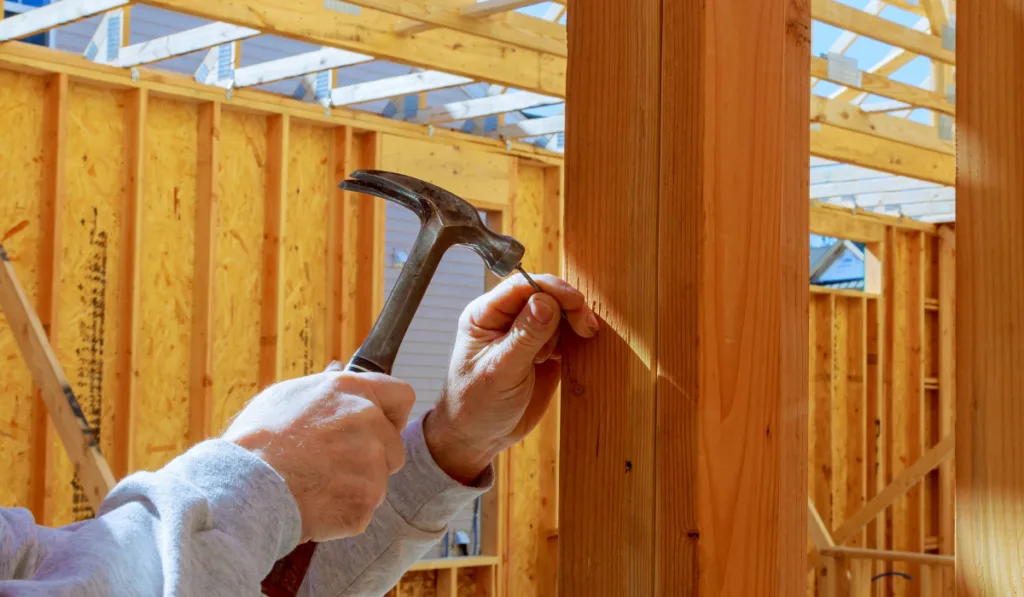 builder hammers a nail into a wooden beam