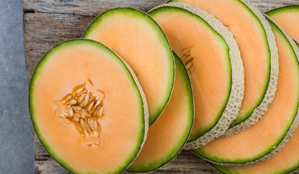 cantaloupe slices on wooden board 