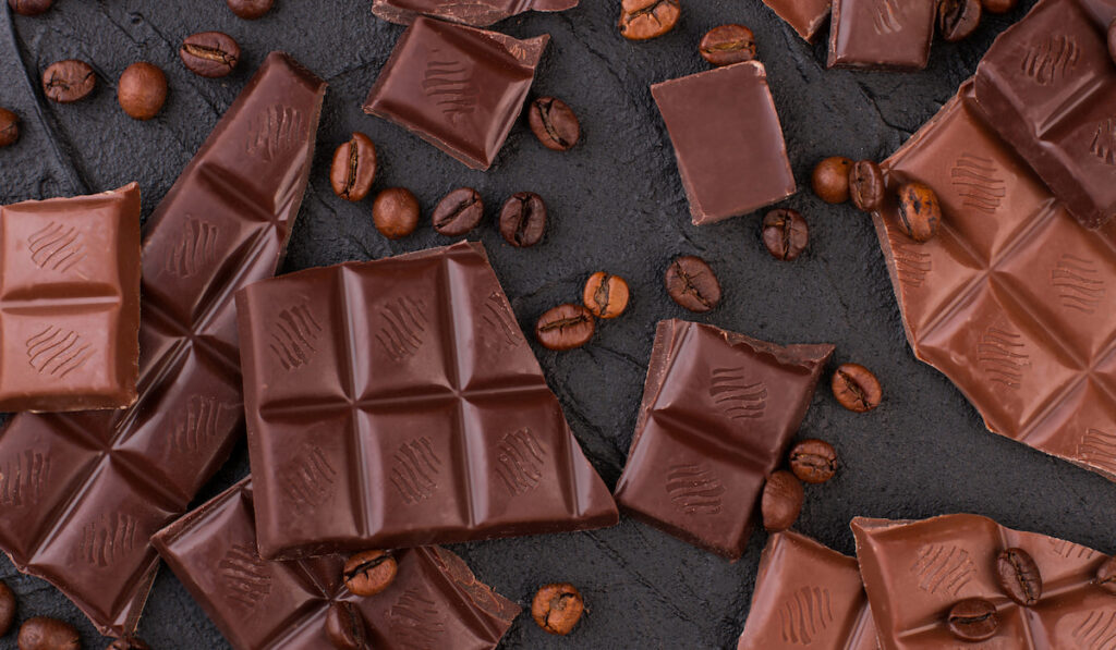 chocolate bars and coffee beans on black background 