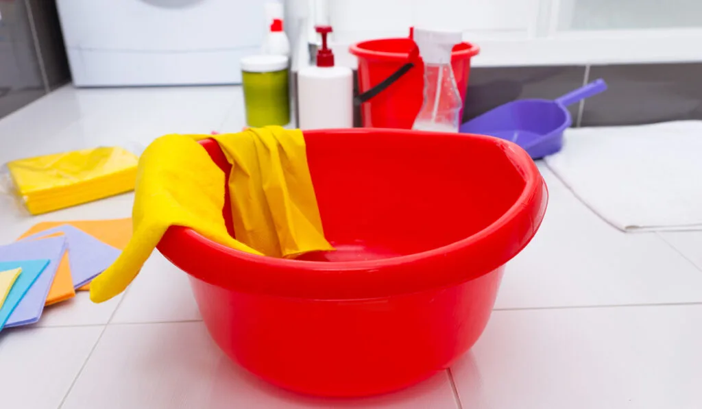 cleaning product detergent glove soap and red tub