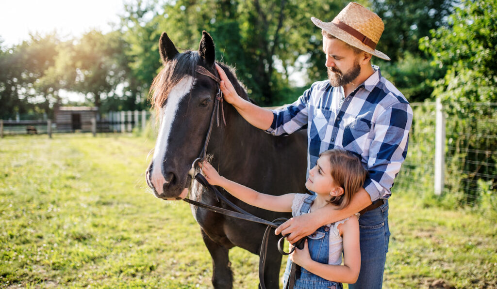father and daughter with small horse on small animal farm