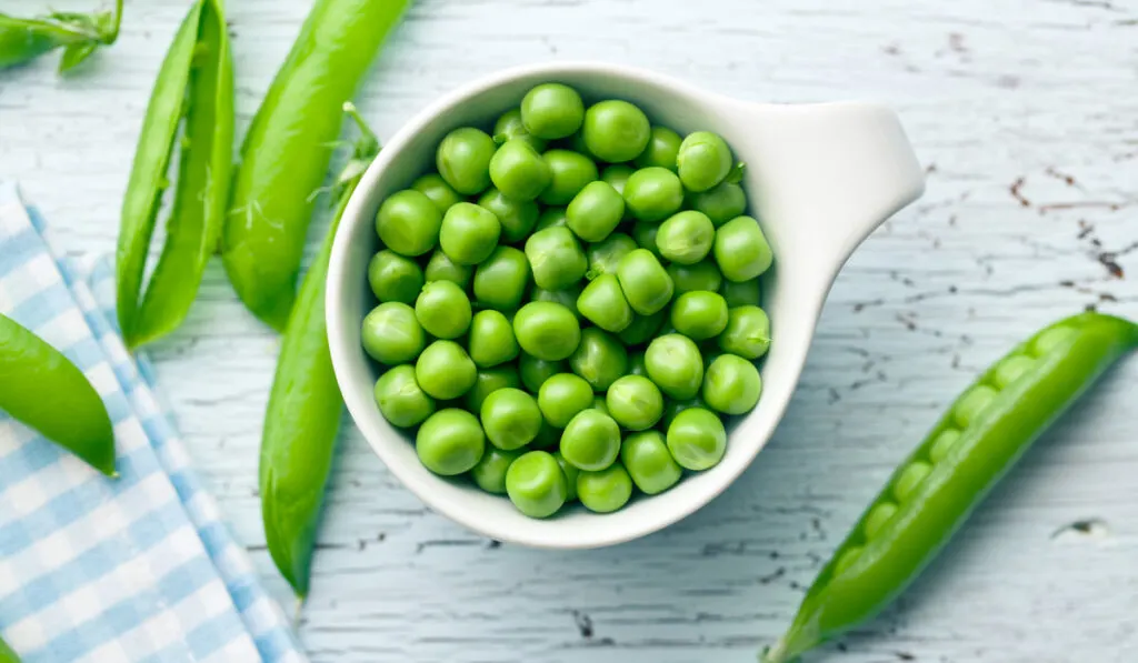 fresh green peas in a glass on white table 