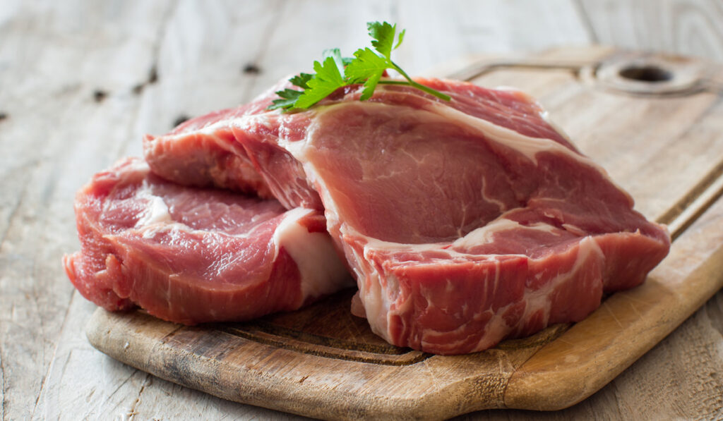 fresh raw pork steaks on chopping board 