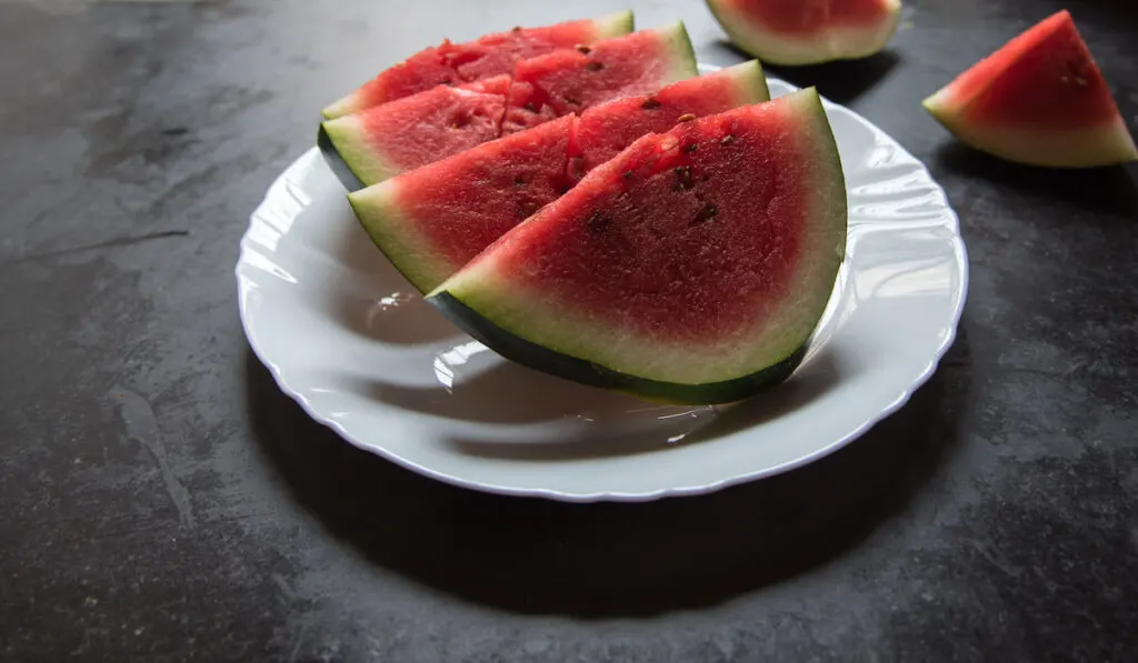 fresh watermelon slices in white plate black background 