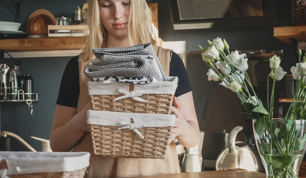 girl fixing decorative basket with different towels 