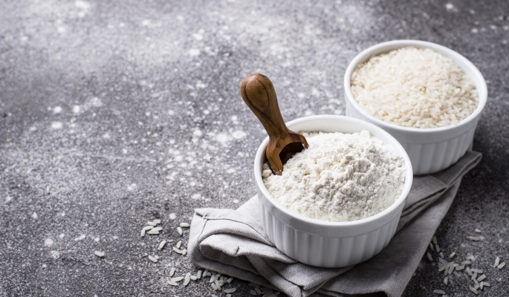 gluten free rice flour and rice in a bowl  on a gray stone texture background