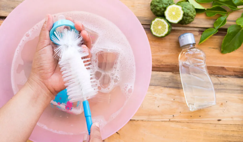 hand of woman cleaning baby bottles using bottle brush