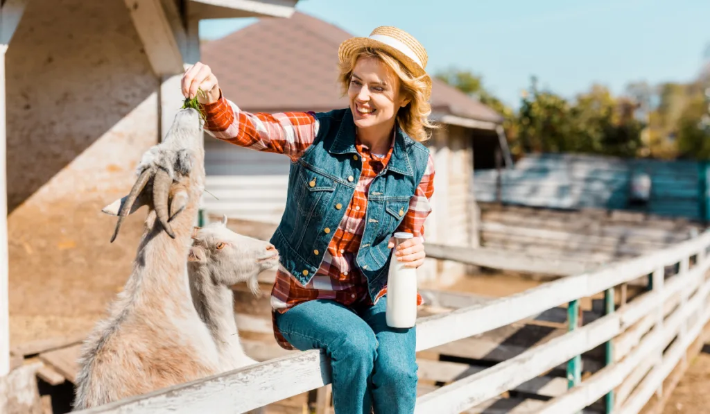 woman feeding a goat holding a bottle of milk