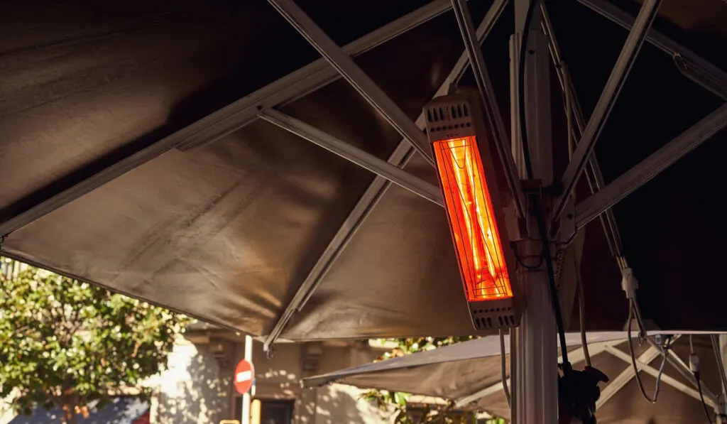 image of street with electric outdoor heater hang on under big umbrella