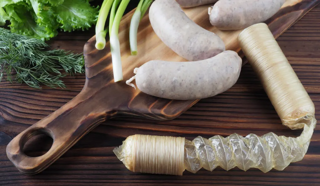 intestines for sausage casing and raw sausages on wooden table