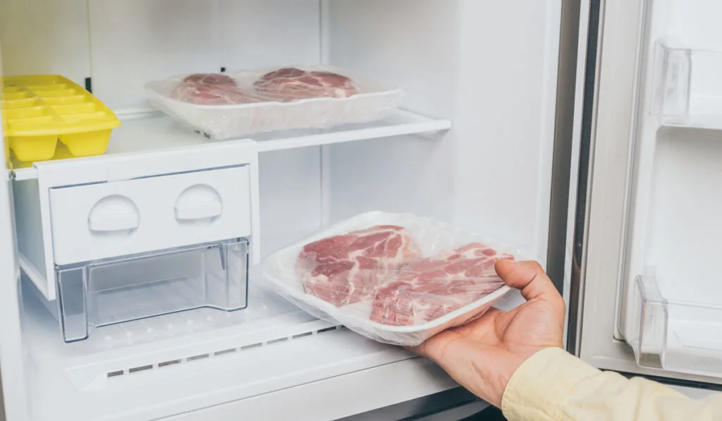 man hands taking out frozen pork from the freezer 