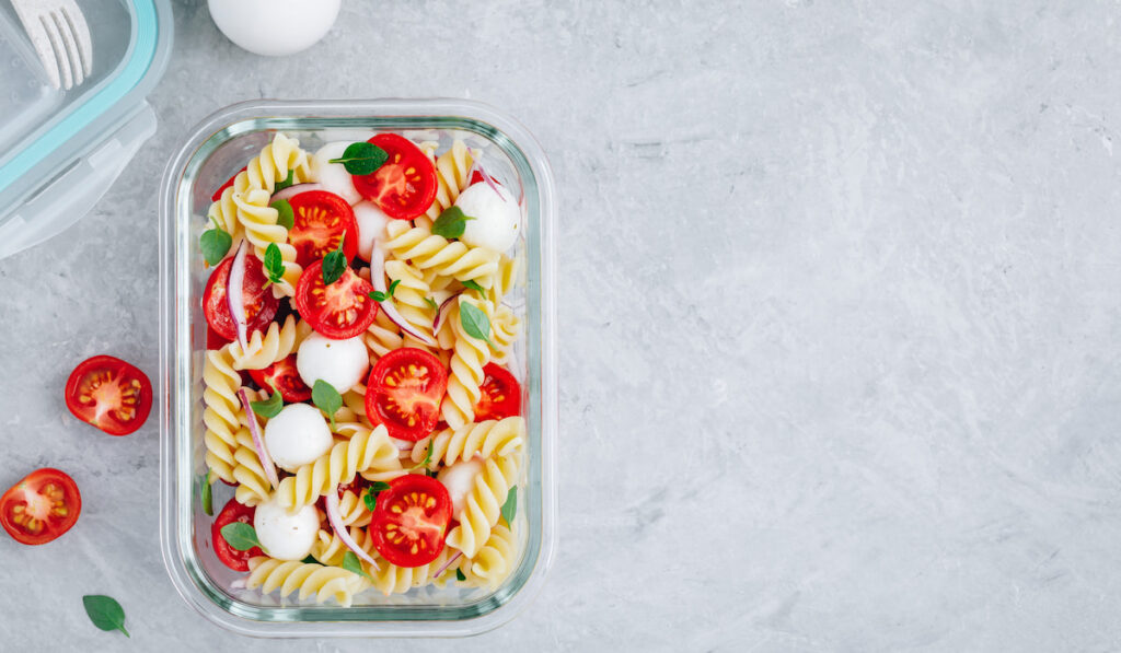 meal container with pasta salad tomatoes onion and cheese
