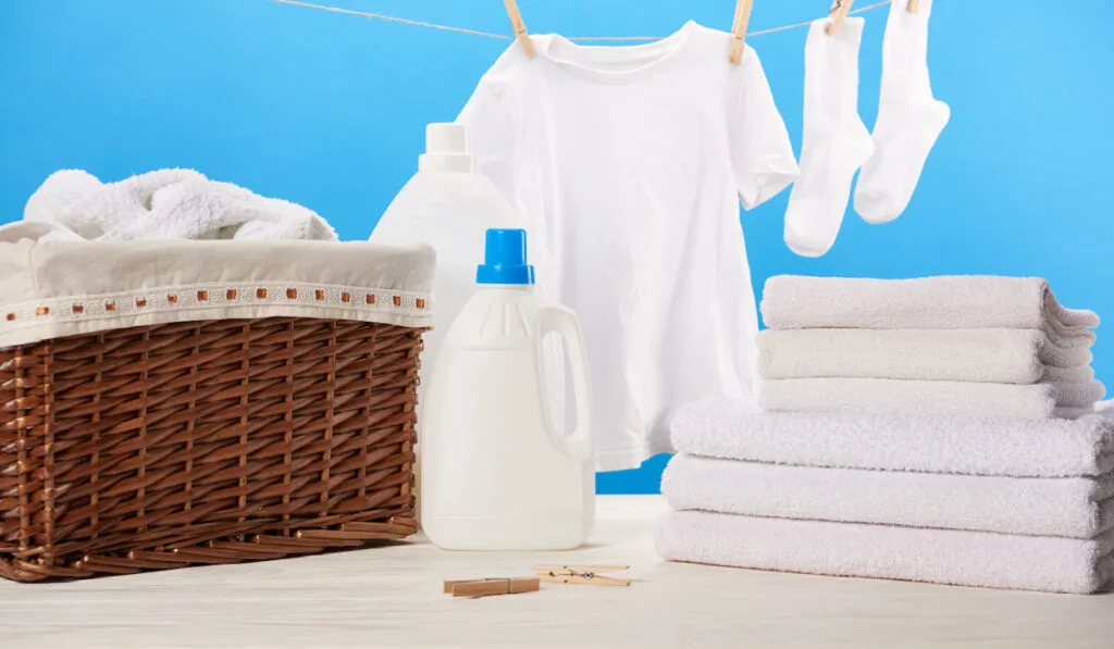 plastic containers with laundry liquids, laundry basket, and clothes 