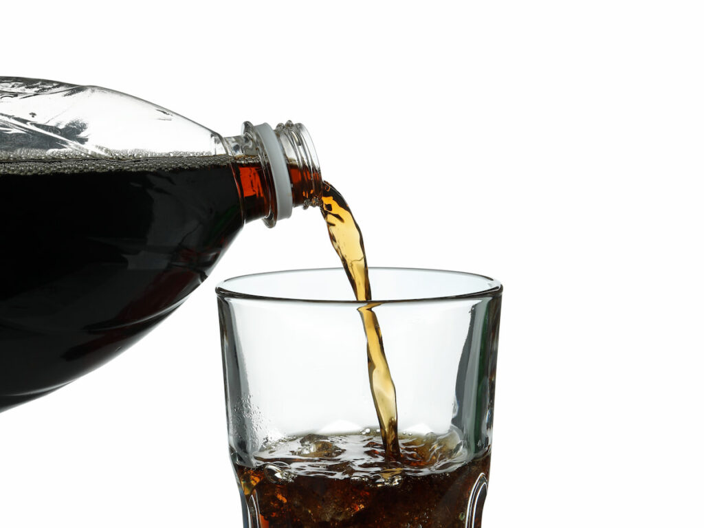pouring cola into a glass on white background 
