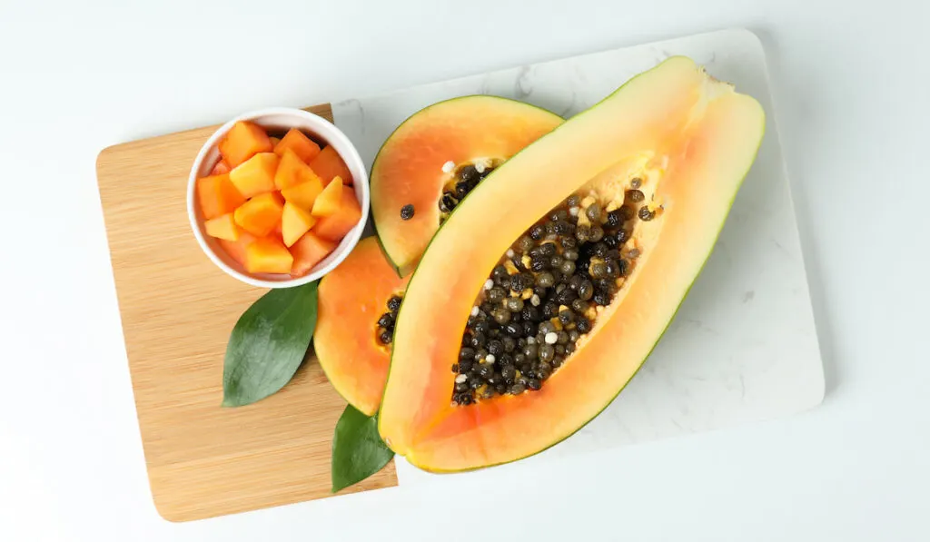 ripe sliced papaya on chopping board on white background 