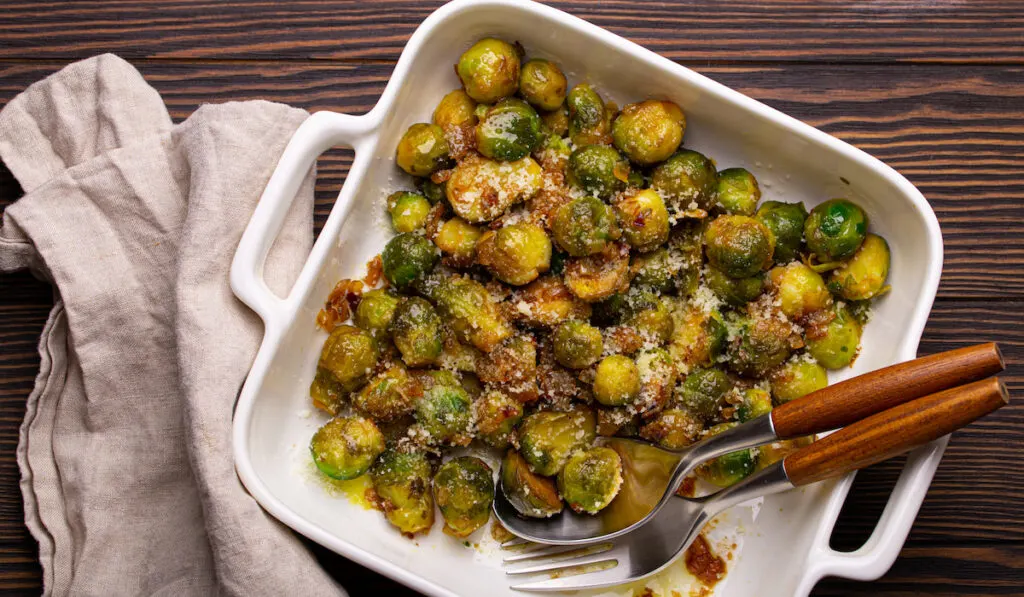roasted brussels sprouts with spoon and fork on wooden table 