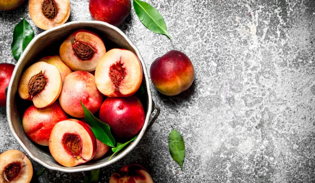 sliced and whole peaches in an old bucket