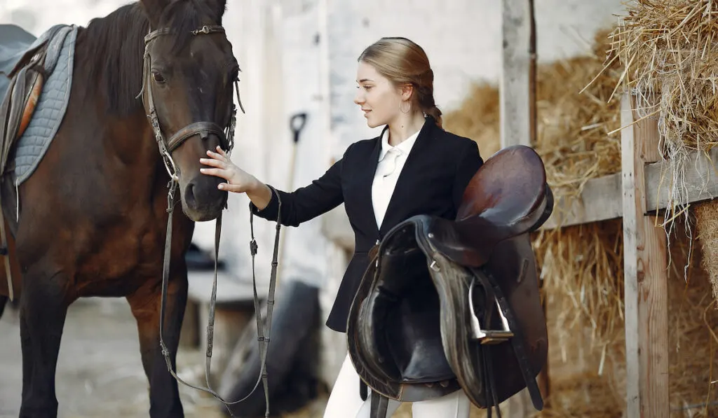 small female rider in black form preparing her big horse