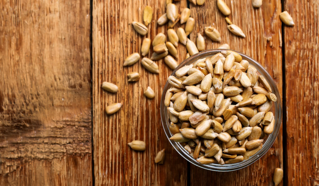 sunflower seeds in a bowl on wooden background 