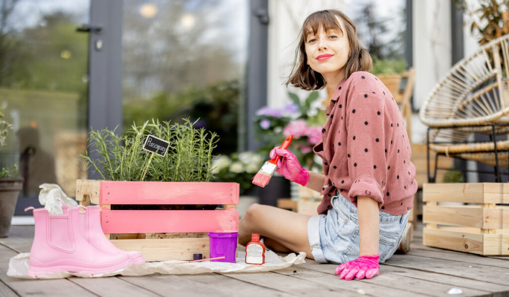 woman painting the planter box with pink paint