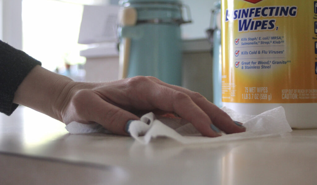 woman's hand wiping down the countertop with disinfecting wipes